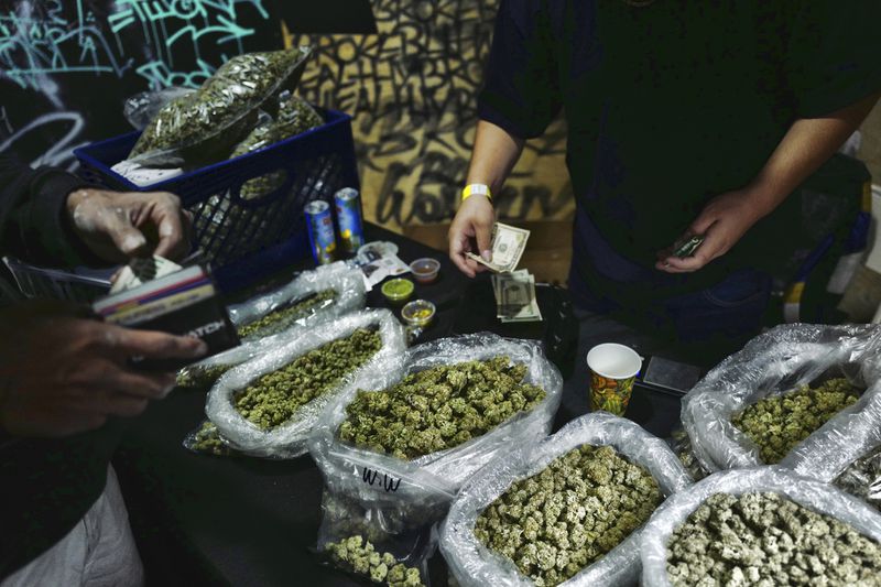 FILE - A vendor makes change for a marijuana customer at a cannabis marketplace in Los Angeles, April 15, 2019. Marijuana advocates are gearing up for Saturday, April 20, 2024. Known as 4/20, marijuana's high holiday is marked by large crowds gathering in parks, at festivals and on college campuses to smoke together. (AP Photo/Richard Vogel, File)