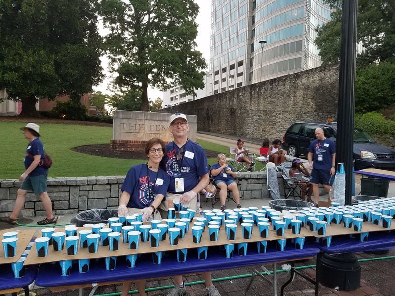 Reva and Steve Schuster, members of The Temple on Peachtree Street, handed out water to runners during the 2018 AJC Peachtree Road Race. PHOTO CONTRIBUTED.