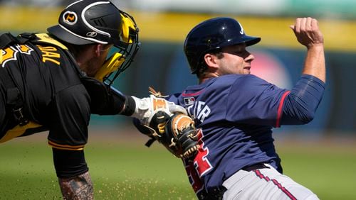 Atlanta Braves second baseman David Fletcher is tagged out by Pittsburgh Pirates catcher Yasmani Grandal, left, while trying to score in the first inning of a spring training baseball game Tuesday, Feb. 27, 2024, in Bradenton, Fla. (AP Photo/Charlie Neibergall)