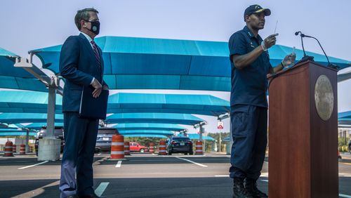 08/10/2020 - College Park, Georgia - Gov. Brian Kemp (left) watches as U.S. Surgeon General Vice Admiral Jerome M. Adams prepares to self-administer a COVID-19 test during a press conference at a drive-thru COVID-19 testing clinic located in a Hartsfield-Jackson International Atlanta Airport paid parking facility in College Park, Monday, August 10, 2020. (ALYSSA POINTER / ALYSSA.POINTER@AJC.COM)