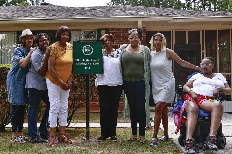The descendants of Charlie Hunter Sr. pose around the home marker on Friday, July 29, 2022. The house is the first in a historic Black neighborhood to receive a home marker. (Natrice Miller/natrice.miller@ajc.com)