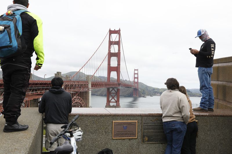 Pedestrians and bicyclists wait outside the pedestrian gate on the south side of the Golden Gate Bridge while the bridge is closed due to protesters on Monday, April 15, 2024 in San Francisco, Calif. (Lea Suzuki/San Francisco Chronicle via AP)
