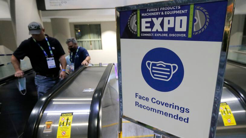 A sign recommending masks sits at the top of the elevator leading down to the convention during the Forest Products Machinery and Equipment Expo in the Georgia World Congress Center on Wednesday, Aug. 11, 2021. The exposition featured equipment manufacturers in the wood processing industry. Due to COVID-19, attendees are required to complete a health survey before entering the convention. Masks are optional. (Christine Tannous / christine.tannous@ajc.com)