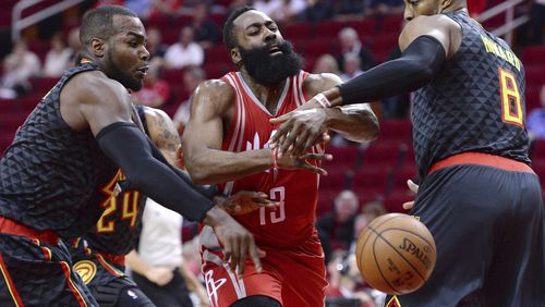 Houston Rockets guard James Harden (13) loses the ball as he drives between Atlanta Hawks forward Paul Millsap, left, and Dwight Howard (8) during the first half of an NBA basketball game Thursday, Feb. 2, 2017, in Houston. (AP Photo/George Bridges)