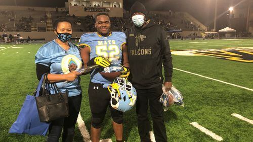 The picture of high school football in 2020: Because of the pandemic, parents' smiles are obscured by masks and, for Mays High, senior night had to be held Friday on the road, at Marist. Here the Wimberly family - Quajulan, Kaleb and Carey - make the best of it.