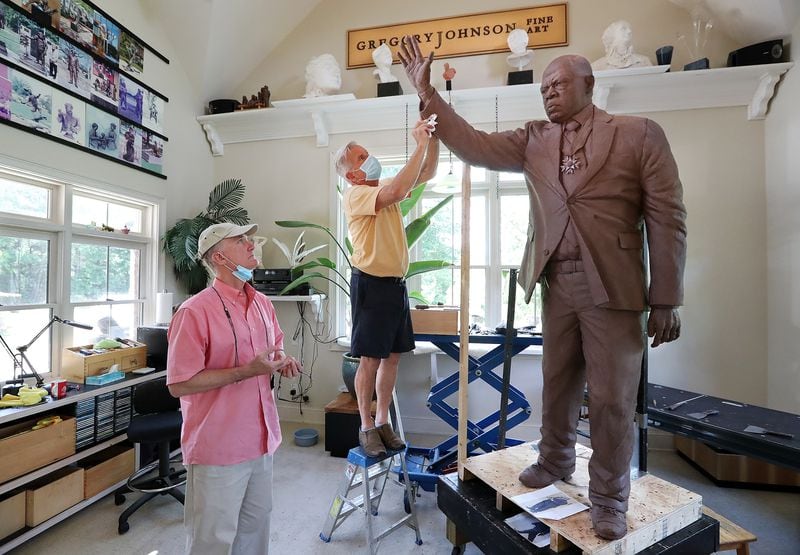 072820 Cumming: Sculptor Gregory Johnson (right) works on a one and one-third life-size statue of John Lewis made with 800 pounds of clay that will be cast in bronze at his studio while patron Rodney Mims Cook Jr. (left) checks on the progress on Tuesday, July 28, 2020 in Cumming.    Curtis Compton ccompton@ajc.com