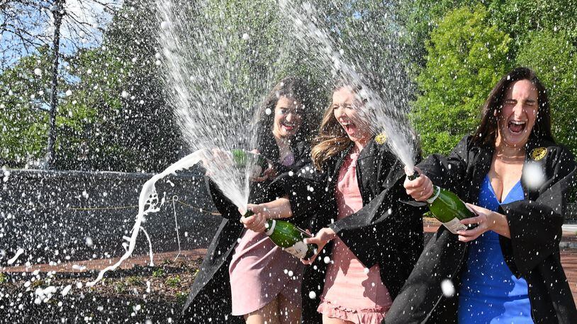 Emory graduate candidates for the class of 2020 (from left) Katie Matuska, Liz Olinde and Izzy Saridakis spray Champagne as they celebrate at Emory's Haygood-Hopkins Gate in Decatur on Saturday, April 25, 2020. They were all roommates and wanted to celebrate their graduation together since they may only have a virtual graduation ceremony this year. (Hyosub Shin / Hyosub.Shin@ajc.com)
