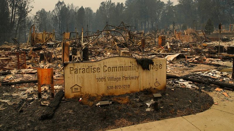 FILE- In this Tuesday, Nov. 13, 2018 file photo a sign stands at a community destroyed by the Camp fire in Paradise, Calif. Most homes are gone, as are hundreds of shops and other buildings. The supermarket, the hardware store, Dolly-O-Donuts & Gifts where locals started their day with a blueberry fritter and a quick bit of gossip, all gone. The town quite literally went up in smoke and flames in the deadliest, most destructive wildfire in California history.