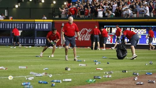 The Atlanta Braves ground crew clean trash off the field after fans littered the area protesting an infield-fly call on Andrelton Simmons in the eighth inning of the National League wild card game against the St. Louis Cardinals at Turner Field in Atlanta on Friday, Oct. 5, 2012. CURTIS COMPTON/CCOMPTON@AJC.COM