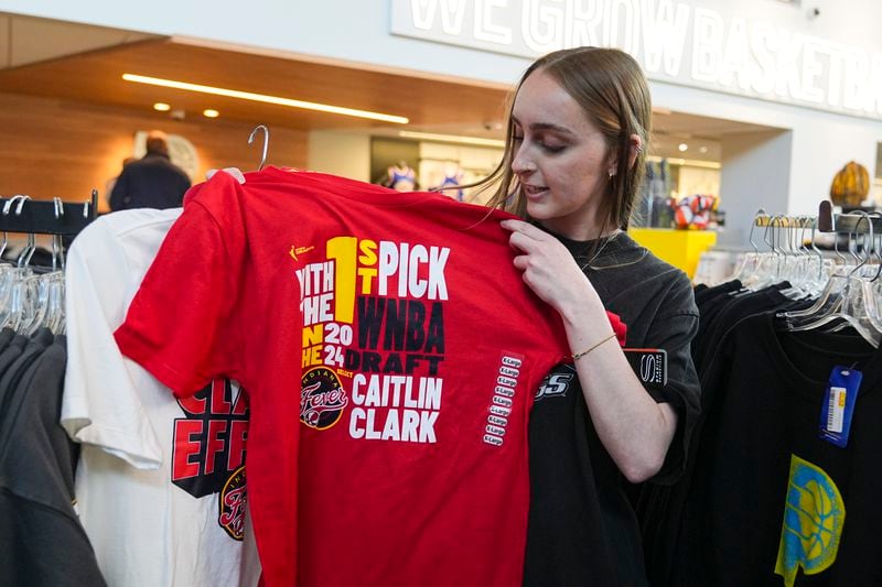 Shelby Tekulve, 20, displays one of the Caitlin Clark shirts she was purchasing in the Indiana Fever team store in Indianapolis, Tuesday, April 16, 2024. The Fever selected Clark as the No. 1 overall pick in the WNBA basketball draft. (AP Photo/Michael Conroy)