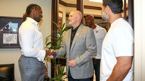 Falcons coach Dan Quinn shaking hands with first-round pick Takkarist McKinley on Sunday outside of his office. Family member in the background and linebackers coach Jeff Ulbrich to the right. (AtlantaFalcons.com)