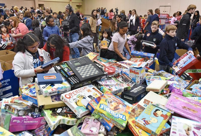 Students and coordinators sort through board game donations during the NFL’s Super Kids-Super Sharing project at the Infinite Energy Forum in Duluth. HYOSUB SHIN / HSHIN@AJC.COM