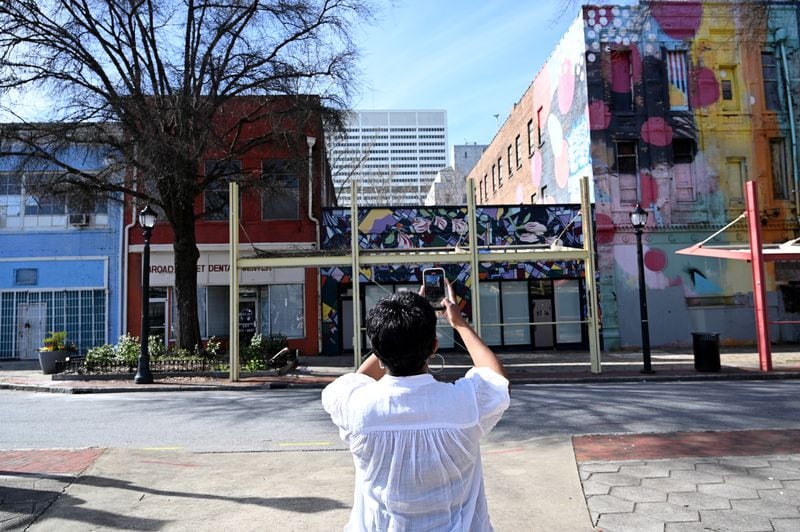 An attendee of a walking tour of South Downtown takes a picture of buildings on Tuesday, March 12, 2024, in Atlanta. (Hyosub Shin / Hyosub.Shin@ajc.com)