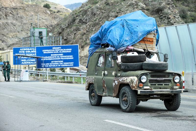 FILE -Sergey Astsetryan, an ethnic Armenian resident of Nagorno-Karabakh, drives his Soviet-made vehicle past Azerbaijani border guard servicemen after been checked at the Lachin checkpoint on the way from Nagorno-Karabakh to Armenia, in Azerbaijan, Sunday, Oct. 1, 2023. A human rights organization representing ethnic Armenians has submitted evidence to the International Criminal Court arguing that Azerbaijan is committing an ongoing genocide against them. (AP Photo/Aziz Karimov, File)