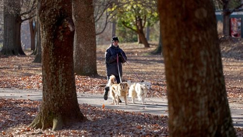 Rand Suffolk, of Atlanta, walks his two dogs Ginger, left, and Sydney, at Piedmont Park on a cold morning, Friday, December 23, 2022, in Atlanta. (Jason Getz / Jason.Getz@ajc.com)