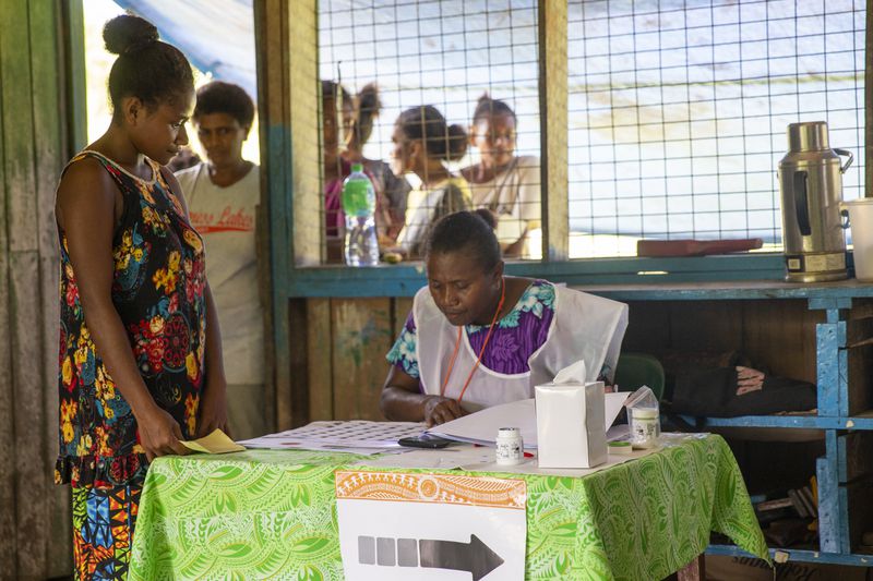 A woman waits to have her name checked on the electoral role before voting during the Solomon Islands elections in a village on the island of San Cristobal, Wednesday, April 17, 2024. Voting has closed across Solomon Islands on Wednesday in the South Pacific nation's first general election since the government switched diplomatic allegiances from Taiwan to Beijing and struck a secret security pact that has raised fears of the Chinese navy gaining a foothold in the region. (AP Photo/Charley Piringi)