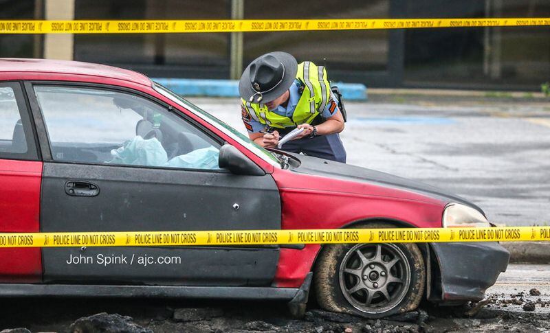 A car on the scene of an officer-involved shooting has a bullet hole in it on Central Avenue. JOHN SPINK / JSPINK@AJC.COM
