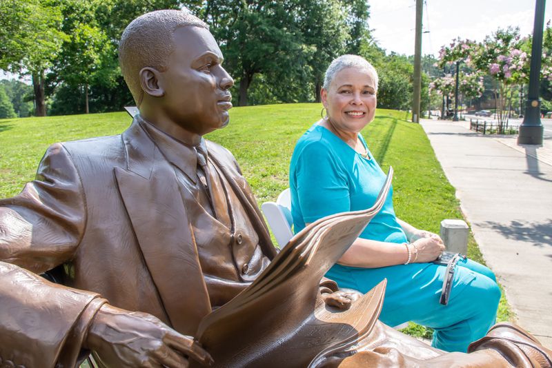 M. Alexis Scott sits beside a sculpture of her grandfather, Black businessman and newspaper publisher William Alexander Scott II, during a celebration of the completed MLK Innovation Corridor at Mozley Park on Tuesday, June 14, 2022. (City of Atlanta)