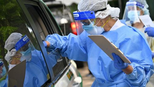 A medical professional collects a nasal swab from a potential COVID-19 patient at a drive-through COVID-19 testing site at Good News Clinic in Gainesville on Tuesday, April 28, 2020. HYOSUB SHIN / HYOSUB.SHIN@AJC.COM