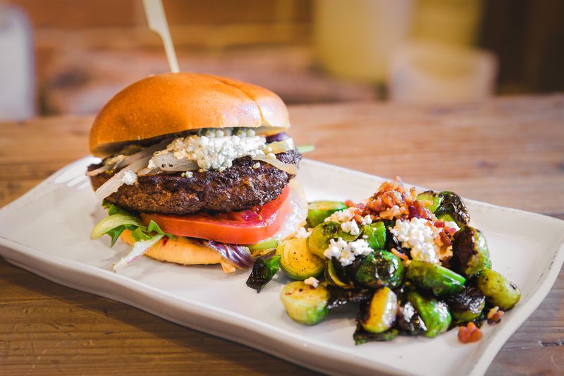Among the burgers at Nick & Norman’s, the Greg’s Pick is a flavor-packed patty made from a blend of ground chuck, short rib and brisket that gets dressed up with blue cheese, lettuce, caramelized onions and a slice of tomato. CONTRIBUTED BY DAVID MCCLONE / NIC & NORMAN’S