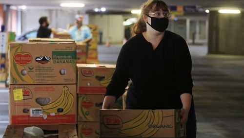 Emily Schubert, volunteer from Rhino Staging, loads food boxes into cars during the Musically Fed food drive on Thursday, October 29, 2020, at the Infinite Energy Center in Duluth, Georgia. Musically Fed is partnering for another food drive for local music industry employees on Dec. 11 at Center Stage.  CHRISTINA MATACOTTA FOR THE ATLANTA JOURNAL-CONSTITUTION.