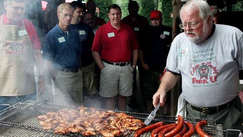 Sam Huff (right) grills some sausage and chicken wings after smoking them during his Lost Mountain Barbecue Company College of Pig Knowledge class a/k/a PorkU. AJC file