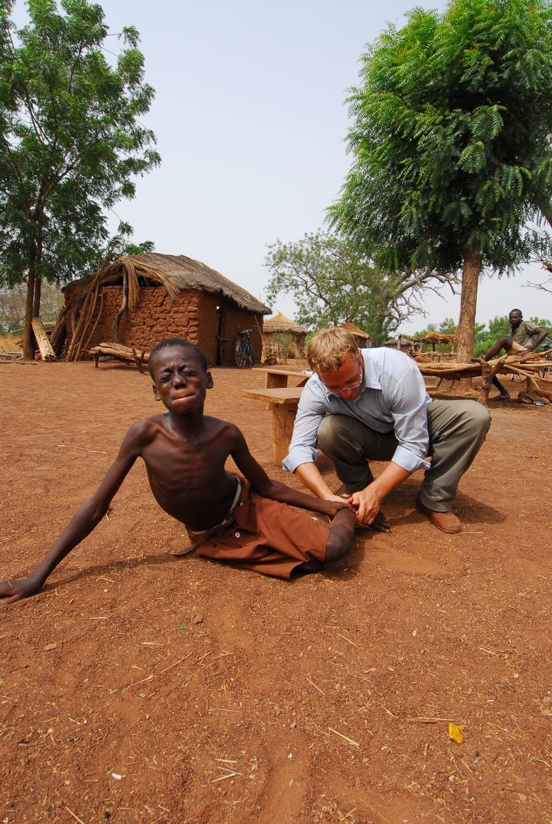 Adam Weiss of the Carter Center tends to a young Guinea worm victim in Africa in this undated photo from The Carter Center. The parasitic disease incubates inside human hosts. After about a year, a long threadlike worm will emerge from the skin of its victim, a painful and debilitating process. (Emily Howard Staub / The Carter Center)