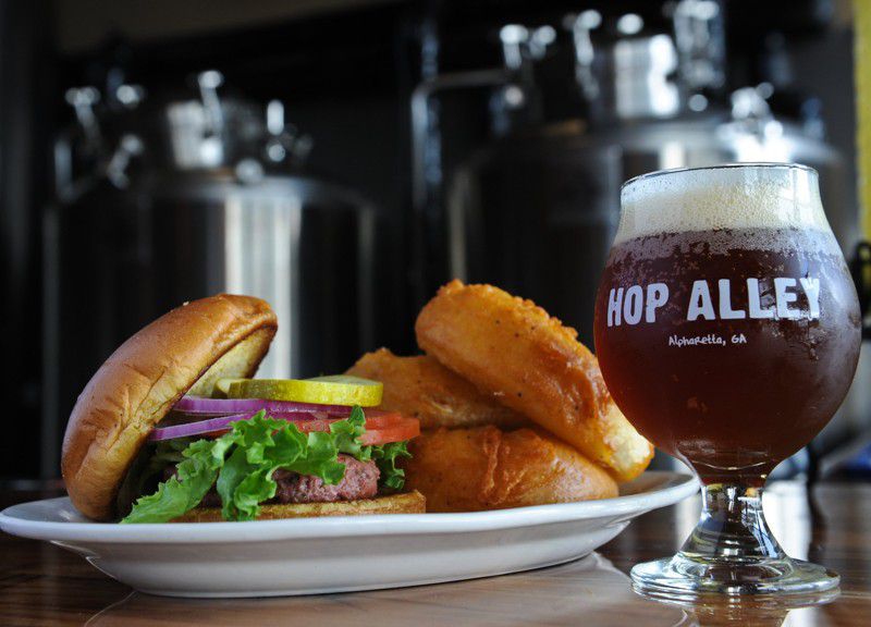 Hop Alley’s Hop Alley Burger uses Angus beef, with lettuce, tomatoes, red onions and pickles. Here, it’s served with onion rings and a beer. (Becky Stein / beckystein.com)
