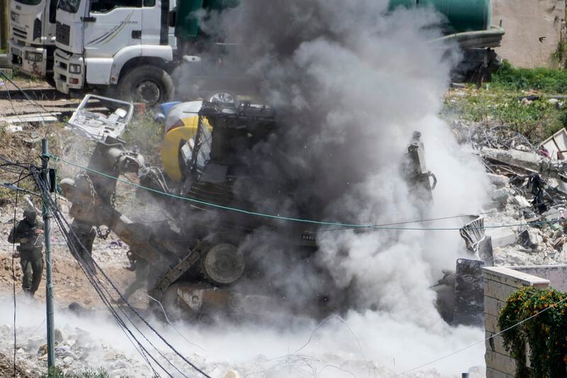 Smoke rises following an explosions raises as Israeli soldiers take cover during a military operation in the Palestinians town of Deir al-Ghusun, near the West Bank town of Tulkarem, Saturday, May 4, 2024. (AP Photo/Majdi Mohammed)