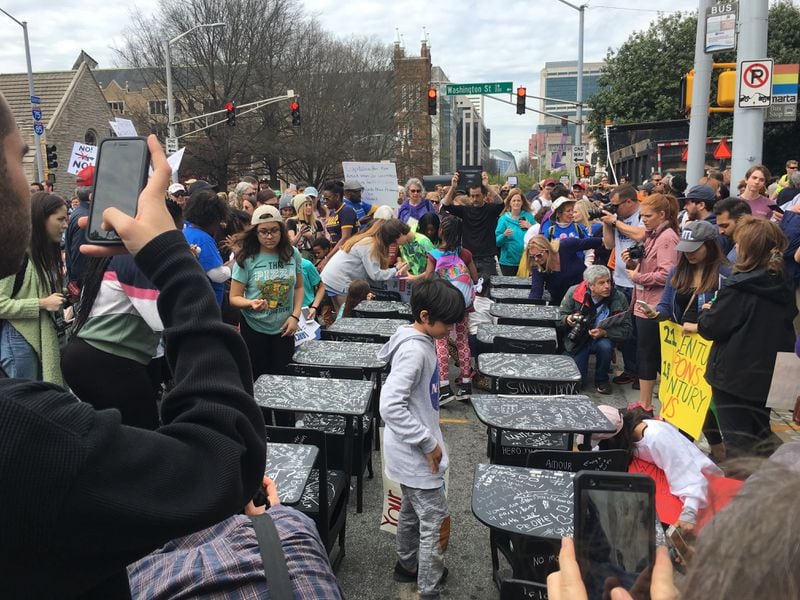 People examine Joseph Guay's exhibition on display in Atlanta: 14 school desks covered in black chalkboard paint in memory of the Parkland,Fla.,  student victims.