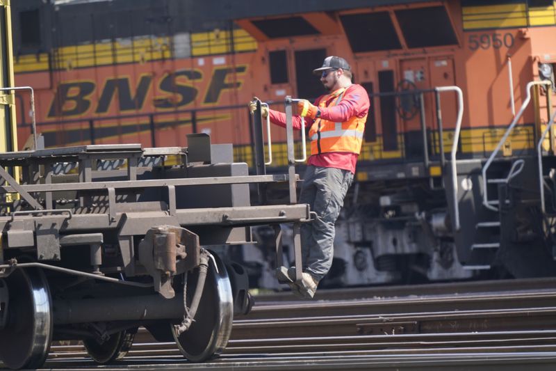 FILE - A worker rides a rail car at a BNSF rail crossing in Saginaw, Texas, Sept. 14, 2022. Four railroads, including BNSF, have asked federal appeals courts to throw out a new rule that would require two-person train crews in most circumstances. (AP Photo/LM Otero, File)