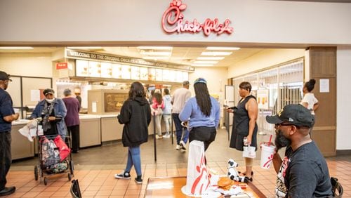 The first Chick-fil-A opened in 1967 in Greenbriar Mall and is now closing on Saturday, May 20, 2023.  Patrons from all over the South, including Marquise Drayton, seated, of Clemson, SC, came to buy one last chicken sandwich from the mall's food court.  Several people remember middle school and friends gathering at the restaurant and some were at the establishment on the first day it opened.  (Jenni Girtman for The Atlanta Journal-Constitution)