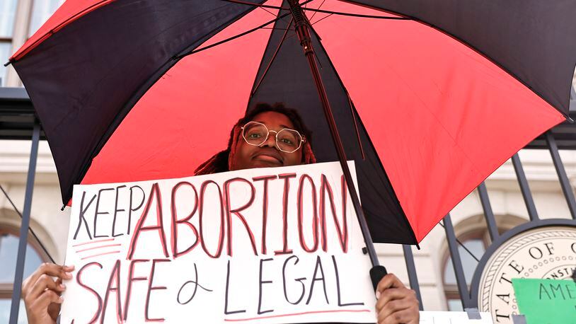 Ashleigh Irvin holds up a “keep abortion safe and legal” sign while standing under an umbrella on Sunday, June 26, 2022. Abortion-rights demonstrators gathered on the steps of The Capitol to protest in response to The Supreme Court’s decision to overturn Roe vs. Wade. (Natrice Miller / natrice.miller@ajc.com)