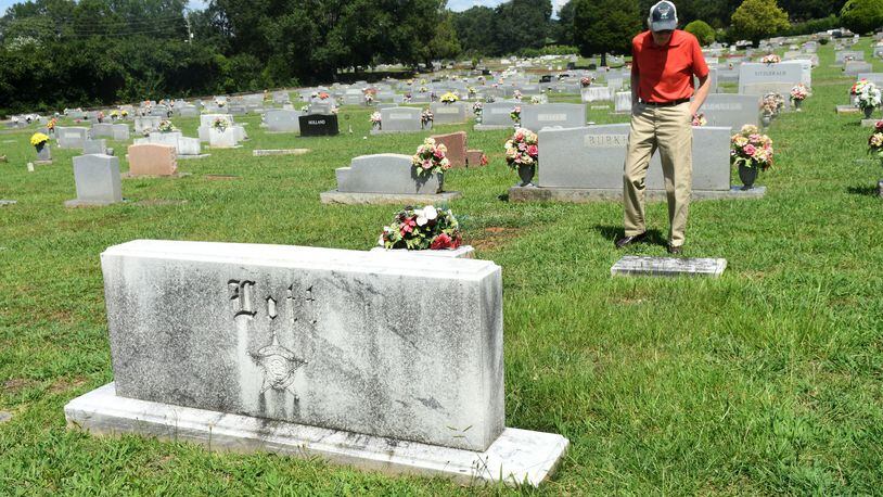 Frank Lott Jr. stands by Polk County Sheriff Frank Lott’s gravestone in Cedartown, Ga., on August 18, 2017. Forty-three years after Frank Lott was shot and killed as he investigated a reported burglary at the local high school, no one has been convicted. There was a suspect who went to trial but a jury acquitted him. Some say Lott’s successor damaged the case by refusing to share information with other agencies investigating the shooting. (Rebecca Breyer)