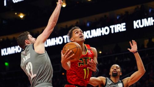 Atlanta Hawks guard Trae Young (11) drives to the basket between Brooklyn Nets forward Joe Harris (12) and Spencer Dinwiddie in the second half of an NBA basketball game Friday, Feb. 28, 2020, in Atlanta. (AP Photo/Tami Chappell)