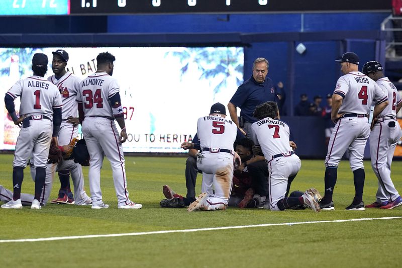 Braves teammates gather around right fielder Ronald Acuna, lying on his back, after he attempted to walk after injuring his knee during the fifth inning Saturday, July 10, 2021, in Miami. (Lynne Sladky/AP)