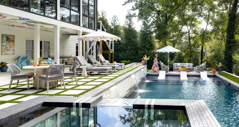 Interior designer Gina Sims used the pool as the centerpiece of this backyard with recliners and an umbrella on one side, a pergola with a swinging bench on another, and a lounge area at the foot of the pool. (Courtesy of Cati Teague)