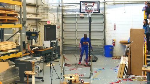 Harlem Globetrotters star Buckets Blake watches a Rube Goldberg machine launch a basketball to a goal at Georgia Tech's digital fabrication lab.