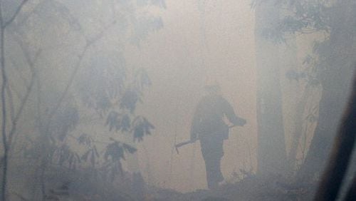 California firefighter Zane Roberts is barely visible through heavy smoke while working on the Rock Mountain fire. CURTIS COMPTON / CCOMPTON@AJC.COM