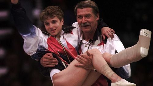In an iconic image, U.S. gymnastics coach Bela Karolyi carries an injured Kerri Strug to the medal ceremony after her vault helped the American women win the team gold medal in the 1996 Olympics at the Georgia Dome. (AJC file photo)