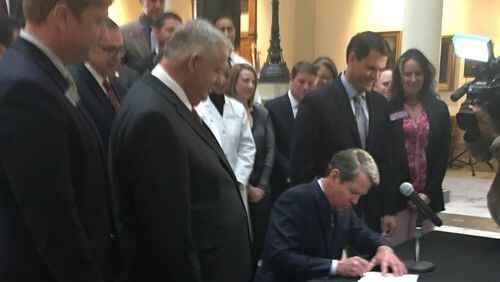 Gov. Brian Kemp, flanked by House Speaker David Ralston and Lt. Gov. Geoff Duncan, signed Senate Bill 106, a bill allowing him to seek Medicaid and Affordable Care Act waivers from the federal government to shape health care programs in Georgia. This week and next Kemp’s office plans is expected to announce those proposals. (PHOTO by Ariel Hart / ahart@ajc.com)