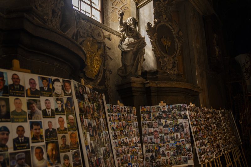 Photographs of Ukrainian soldiers killed during Russian Ukrainian war are displayed at the Saints Peter and Paul church in Lviv, Ukraine, Tuesday, April 16, 2024. (AP Photo/Francisco Seco)