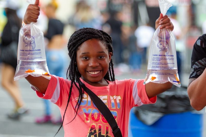 Cordariuna Baisden holds up the four goldfish she won by successfully throwing ping-pong balls into a bowl while at the Atlanta Fair on Sunday, March 6, 2022. (Photo by Steve Schaefer for The Atlanta Journal-Constitution)