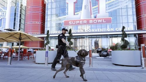 Officer Keith McCart, of the Long Beach, Calif., Police Department, patrols with K-9 Pidura outside the George R. Brown Convention Center, site of the Super Bowl’s media center and the NFL Experience attraction. (AP Photo/David J. Phillip)