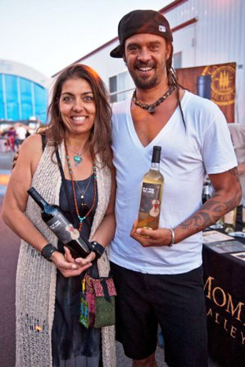 Valentina Guolo-Migotto, owner of Ca’ Momi, and singer, song writer and health nut Michael Franti hold bottles of Do It For The Love wines. Ca' Momi makes the wine and proceeds support the charity that brings people with life-threatening illnesses to live music shows. (image Lyle A. Waisman)