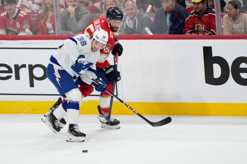 Tampa Bay Lightning left wing Brandon Hagel (38) and Florida Panthers defenseman Aaron Ekblad (5) battle for the puck during the first period of Game 1 of the first-round of an NHL Stanley Cup Playoff series, Sunday, April 21, 2024, in Sunrise, Fla. (AP Photo/Wilfredo Lee)