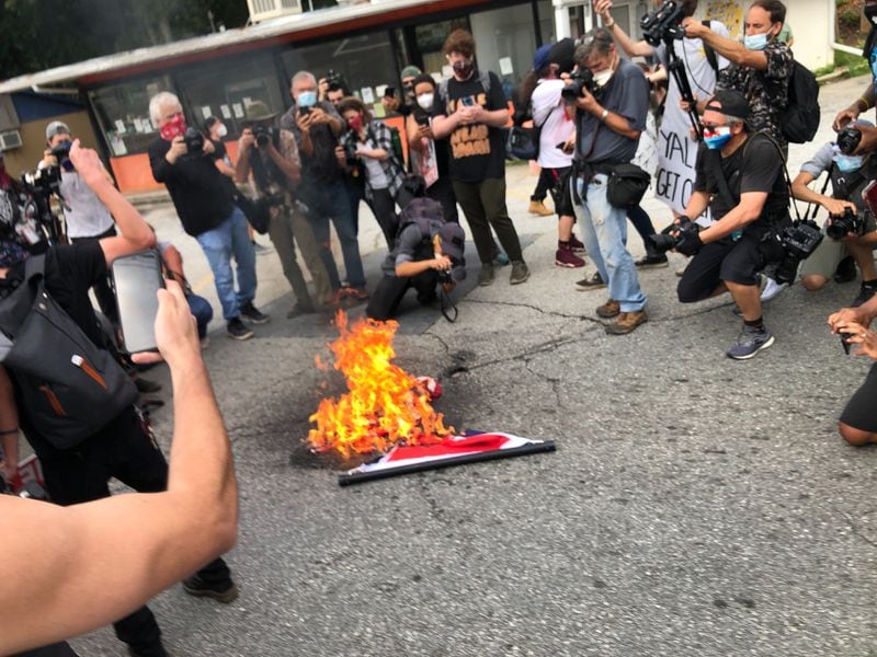 Saturday, Aug. 15, 2020, Stone Mountain --Counter-protesters burn a Confederate flag that was taken from a militia group member in Stone Mountain.