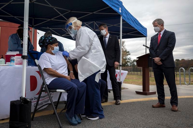 State Senator Ben Watson, right, watches one of the first vaccinations of the Pfizer-BioNTech COVID-19 vaccine given to healthcare workers in Savannah on Tuesday.  (AJC Photo / Stephen B. Morton)
