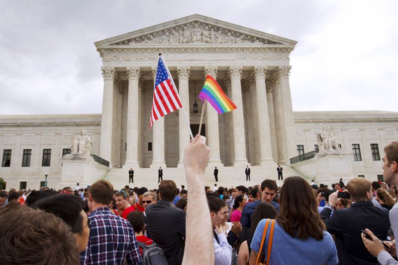 FILE - In this June 26, 2015 file photo, a man holds a U.S. and a rainbow flag outside the Supreme Court in Washington after the court legalized gay marriage nationwide. (AP Photo/Jacquelyn Martin)