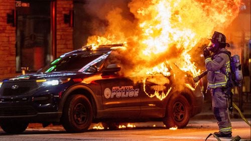 Atlanta firefighters prepared to extinguish a police car that was set on fire during a protest in Atlanta on Saturday. The Atlanta Police Department said several arrests had been made. (Steve Schaefer/The Atlanta Journal-Constitution/TNS)